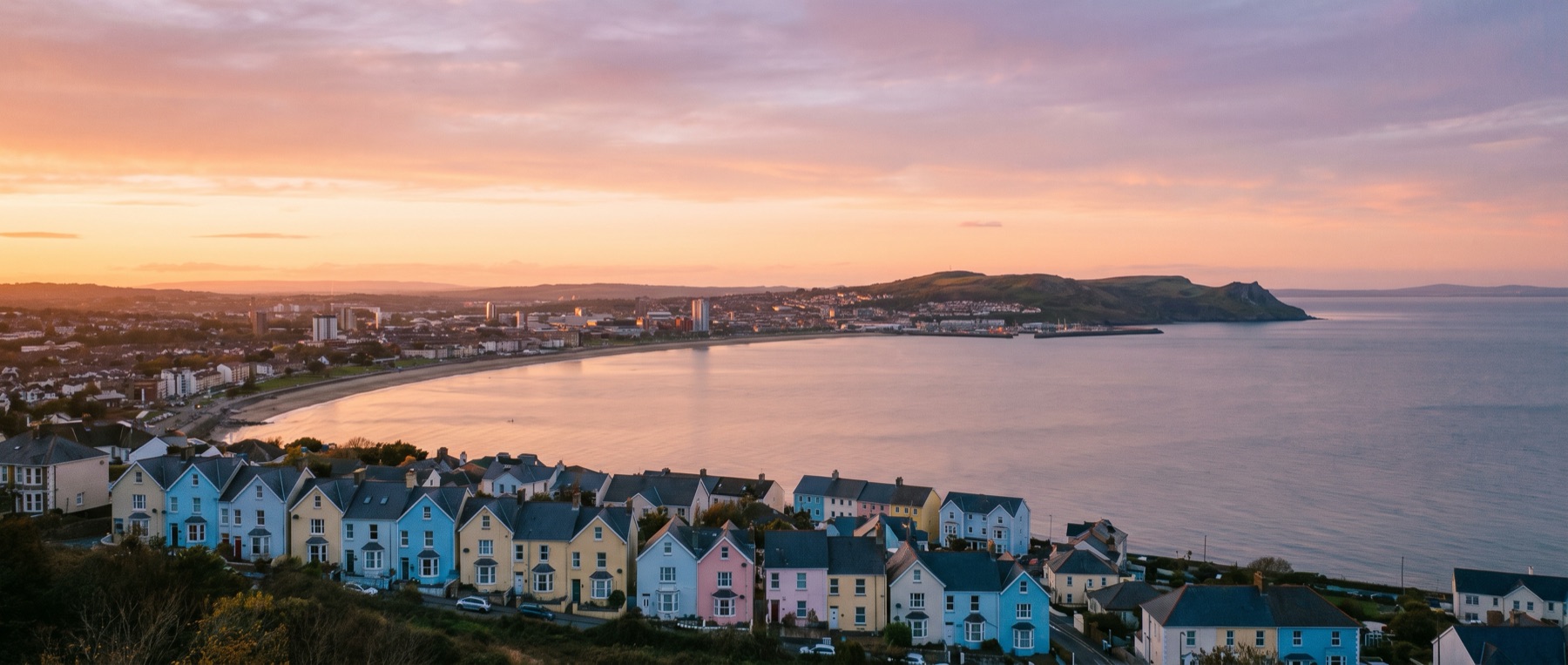 Colourful coastal homes overlooking Mumbles Bay at sunset